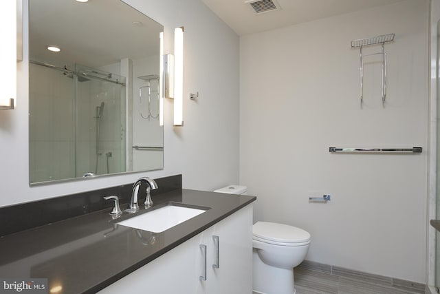 bathroom featuring vanity, toilet, and a shower with shower door