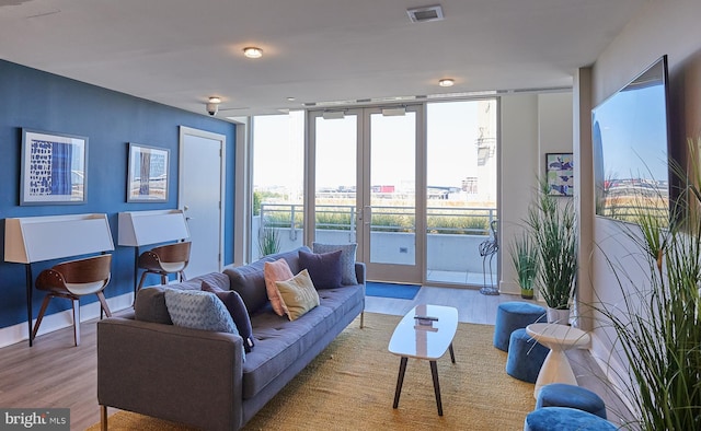 living room featuring french doors, a wall of windows, and light hardwood / wood-style flooring