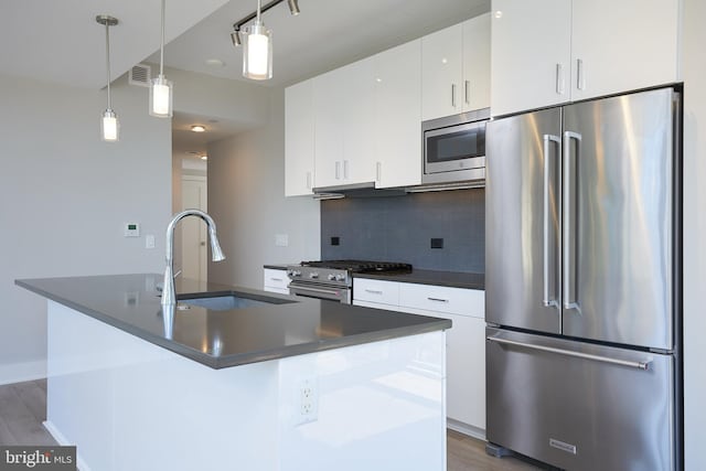 kitchen with a kitchen island with sink, premium appliances, decorative light fixtures, and sink