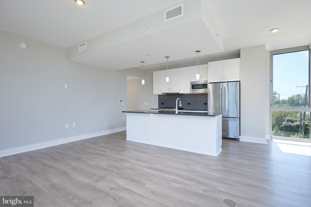 kitchen with hanging light fixtures, stainless steel appliances, tasteful backsplash, light hardwood / wood-style floors, and white cabinets