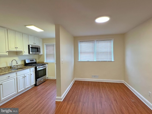 kitchen featuring appliances with stainless steel finishes, sink, white cabinets, and light wood-type flooring