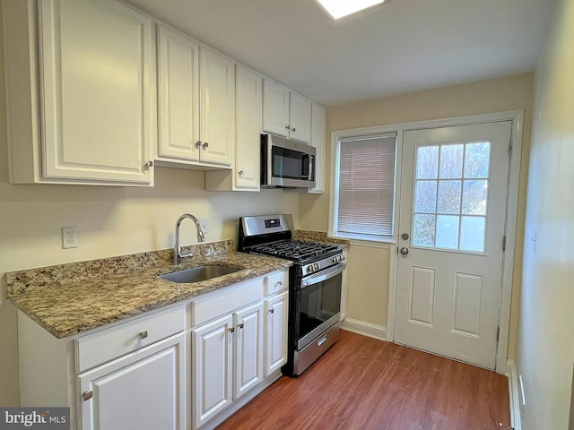 kitchen featuring sink, white cabinets, light stone counters, light hardwood / wood-style floors, and stainless steel appliances