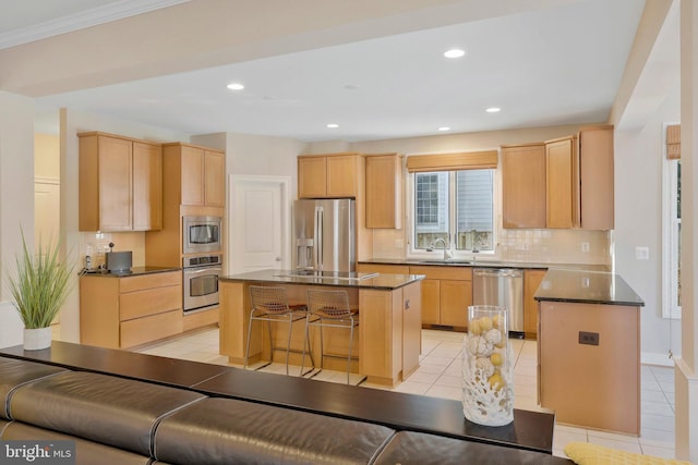 kitchen with stainless steel appliances, a kitchen island, a kitchen breakfast bar, and light brown cabinetry