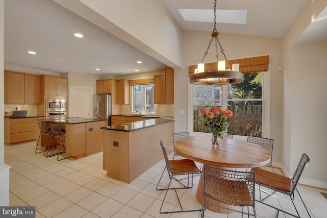 kitchen featuring appliances with stainless steel finishes, pendant lighting, sink, backsplash, and a center island