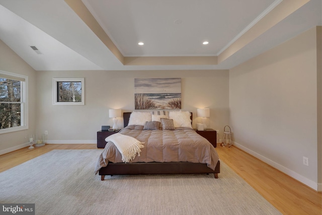 bedroom featuring a tray ceiling and light hardwood / wood-style flooring