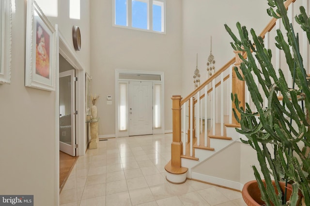 foyer with a towering ceiling and light tile patterned floors