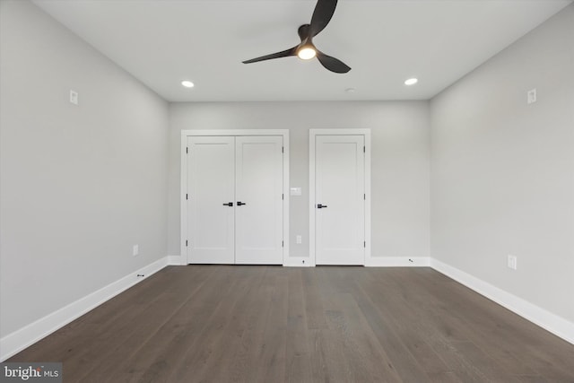 unfurnished bedroom featuring dark wood-type flooring, two closets, and ceiling fan