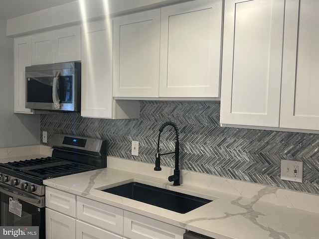 kitchen featuring appliances with stainless steel finishes, sink, and white cabinets