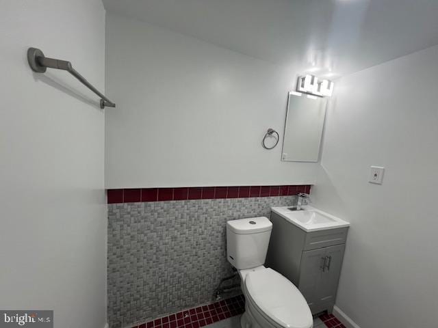 bathroom with vanity, toilet, and tile walls