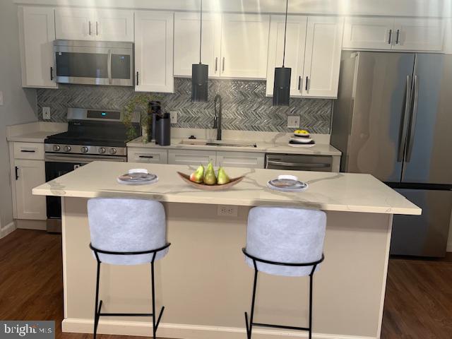 kitchen featuring white cabinetry, appliances with stainless steel finishes, a center island, and sink