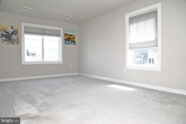 spare room with a healthy amount of sunlight, carpet floors, and visible vents