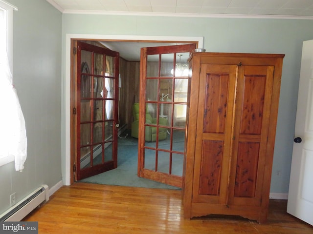 unfurnished dining area featuring crown molding, a baseboard heating unit, light hardwood / wood-style floors, and french doors