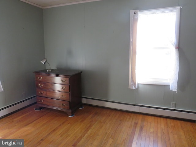 unfurnished bedroom featuring crown molding, a baseboard radiator, and light wood-type flooring