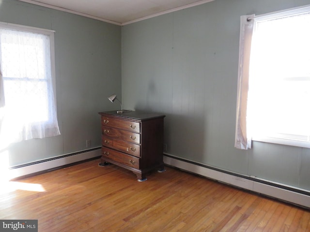 unfurnished bedroom with ornamental molding, a baseboard radiator, and light hardwood / wood-style floors