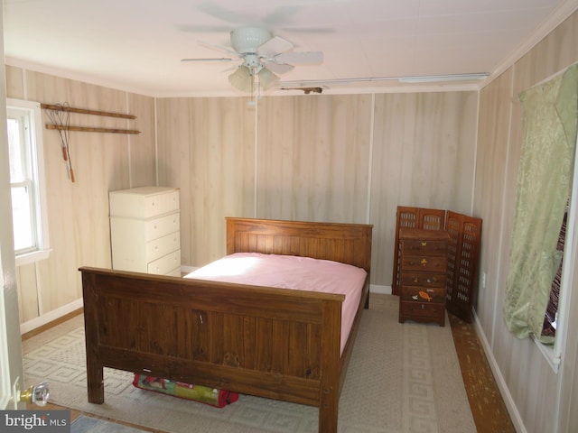 bedroom featuring ceiling fan, ornamental molding, and wooden walls