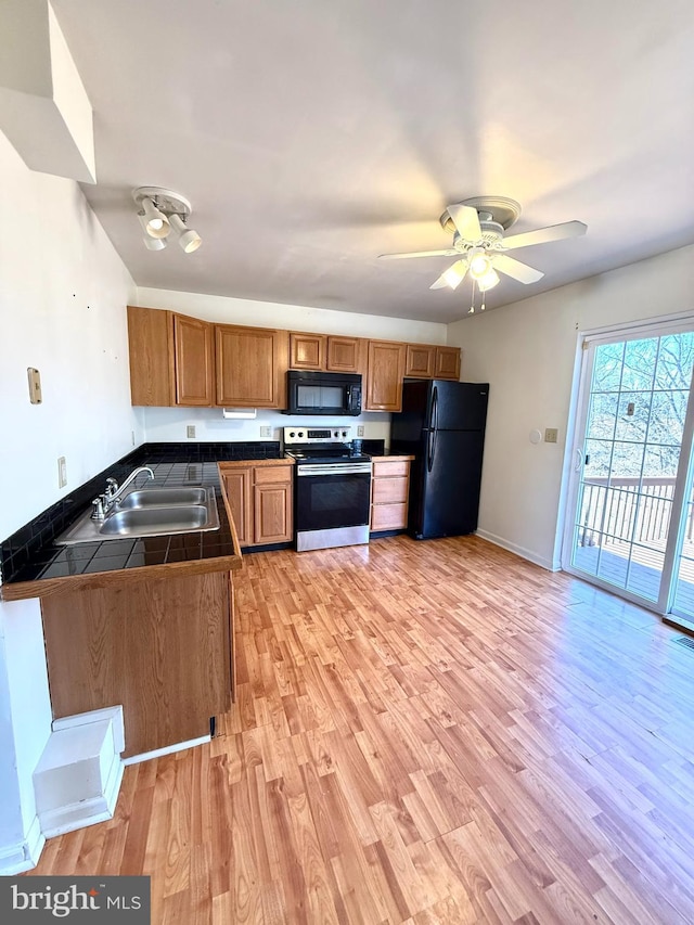 kitchen with black appliances, sink, ceiling fan, kitchen peninsula, and light hardwood / wood-style flooring