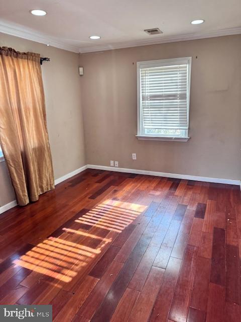 empty room with hardwood / wood-style floors and ornamental molding