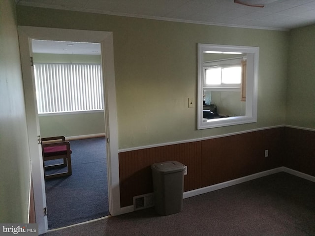 spare room with crown molding and dark carpet