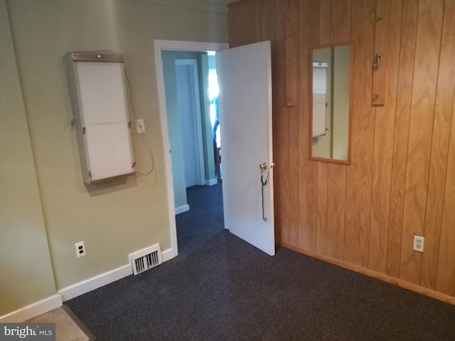 carpeted empty room featuring electric panel and wood walls