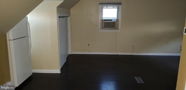 additional living space with cooling unit, dark hardwood / wood-style flooring, and vaulted ceiling