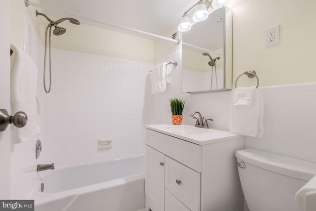 full bathroom with tile walls, vanity, tiled shower / bath combo, and toilet