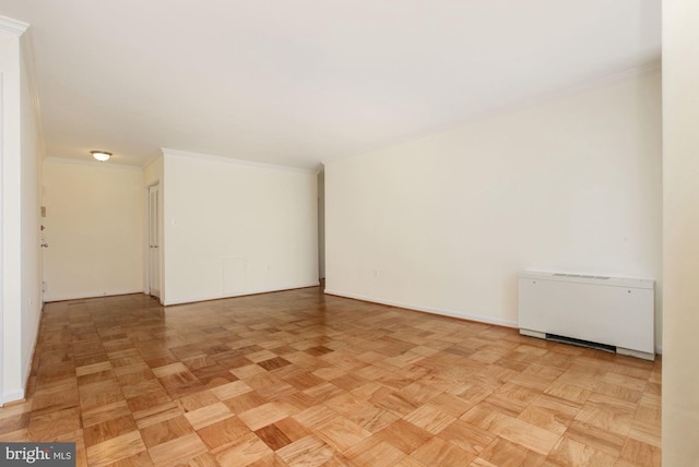 spare room with radiator heating unit, ornamental molding, and light parquet floors