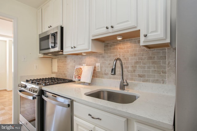 kitchen featuring light stone counters, sink, white cabinets, and appliances with stainless steel finishes