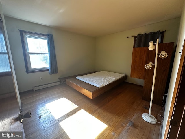 bedroom with wood-type flooring and baseboard heating