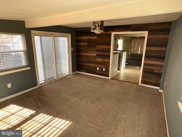 carpeted empty room with ceiling fan and wooden walls