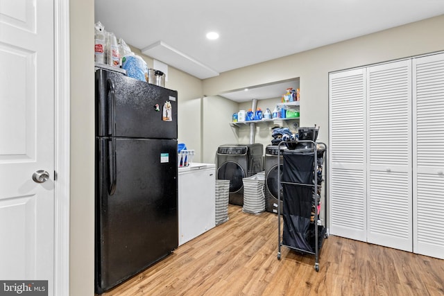 kitchen featuring light wood-type flooring, independent washer and dryer, and black fridge