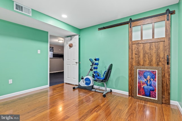 workout area with a barn door and hardwood / wood-style floors