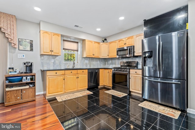 kitchen with appliances with stainless steel finishes, light brown cabinetry, sink, backsplash, and dark hardwood / wood-style flooring