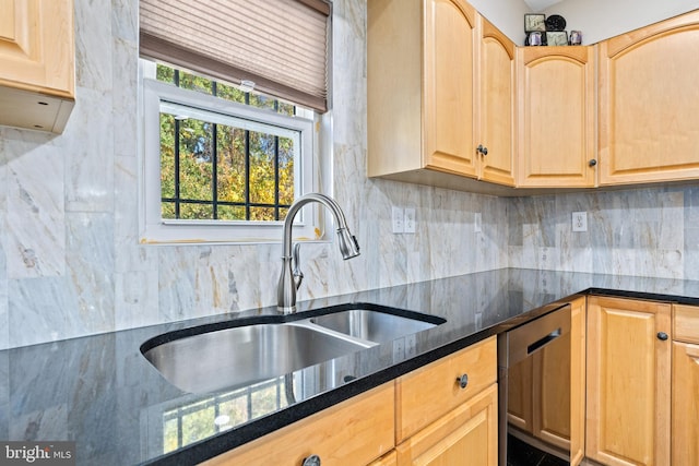 kitchen featuring light brown cabinetry, dishwasher, sink, backsplash, and dark stone counters