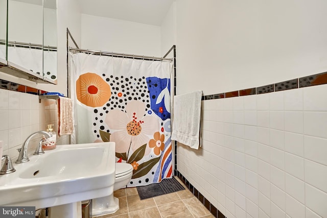 bathroom featuring sink, tile walls, tile patterned flooring, curtained shower, and toilet