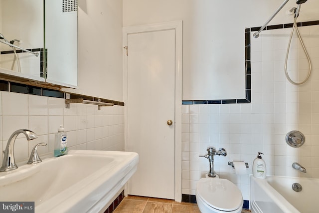 full bathroom featuring tile walls, sink, toilet, and tiled shower / bath