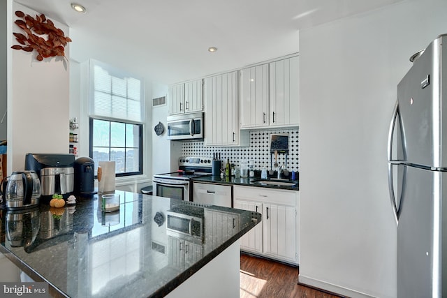 kitchen featuring sink, white cabinets, decorative backsplash, dark stone counters, and stainless steel appliances