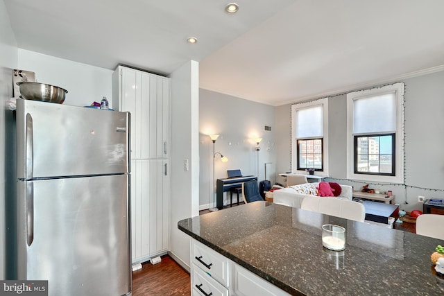 kitchen featuring crown molding, dark wood-type flooring, stainless steel fridge, white cabinets, and dark stone counters