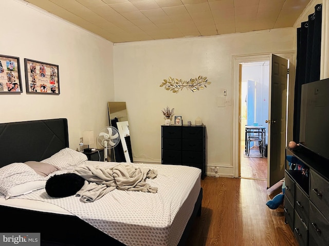 bedroom featuring ornamental molding and dark hardwood / wood-style flooring