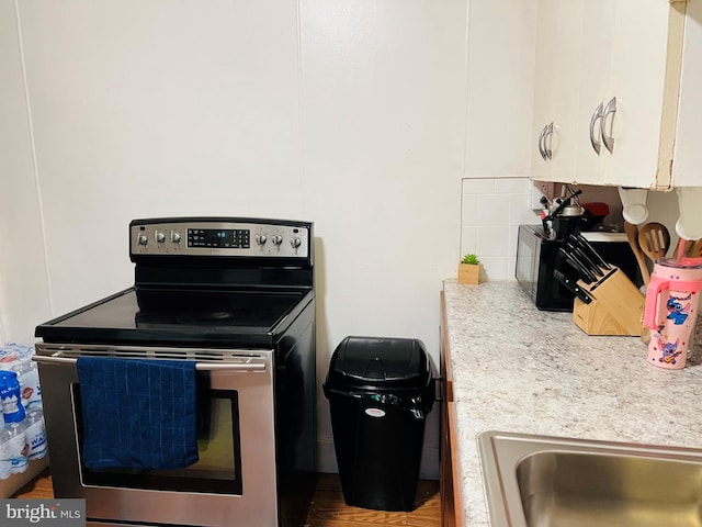 kitchen featuring white cabinets, backsplash, and electric stove