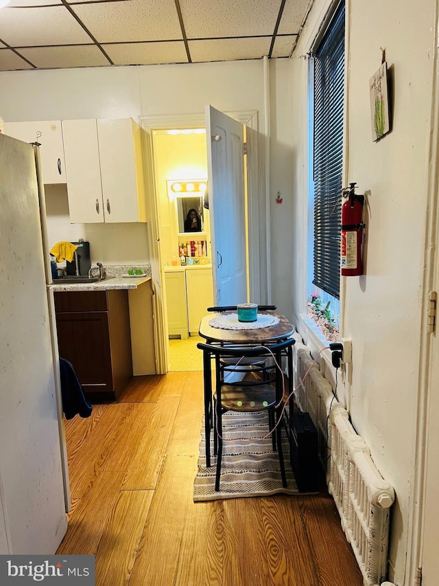 kitchen featuring a paneled ceiling, white cabinetry, light hardwood / wood-style floors, washer and dryer, and decorative backsplash