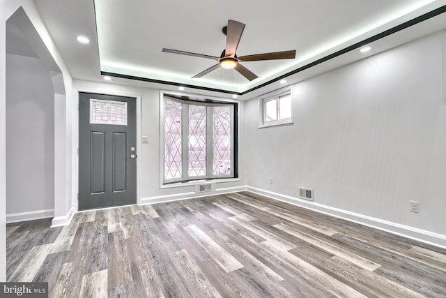 foyer entrance featuring hardwood / wood-style flooring, ceiling fan, and a raised ceiling