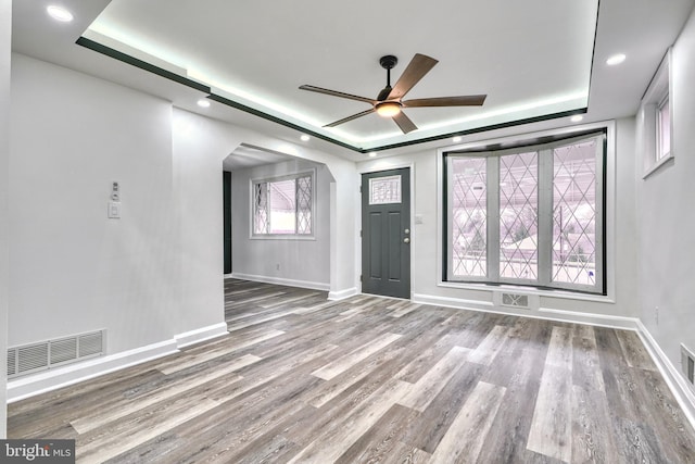 unfurnished room featuring a tray ceiling, ceiling fan, and hardwood / wood-style flooring