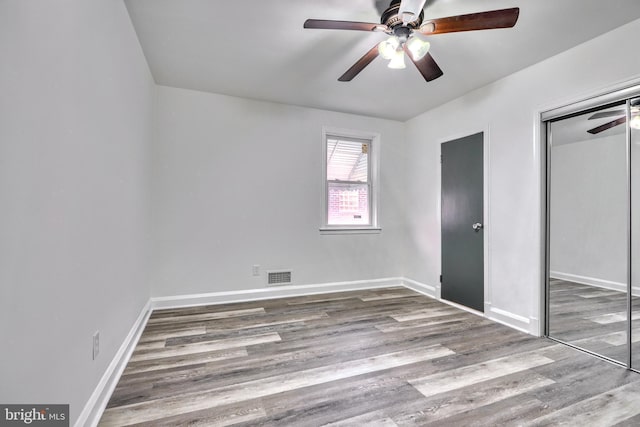 unfurnished bedroom featuring ceiling fan, hardwood / wood-style floors, and a closet