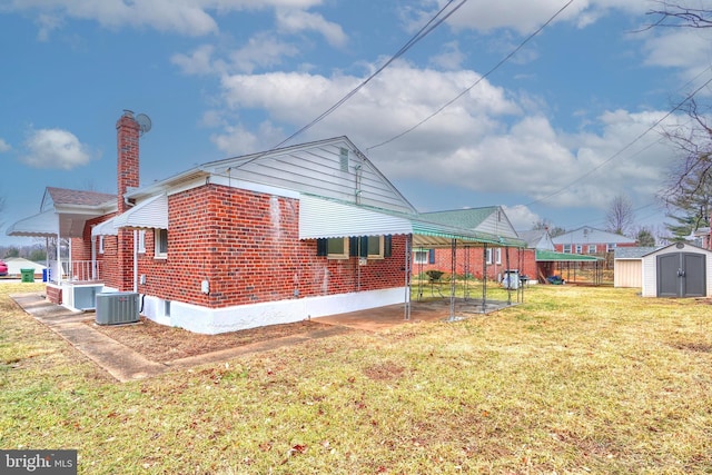 rear view of house with a yard, central AC, and a shed