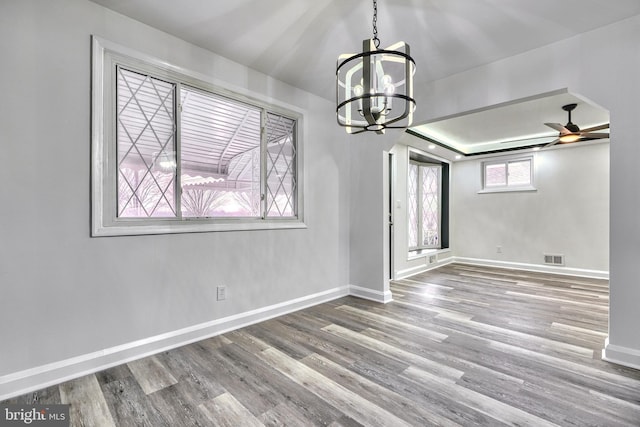 unfurnished dining area featuring hardwood / wood-style flooring and ceiling fan with notable chandelier