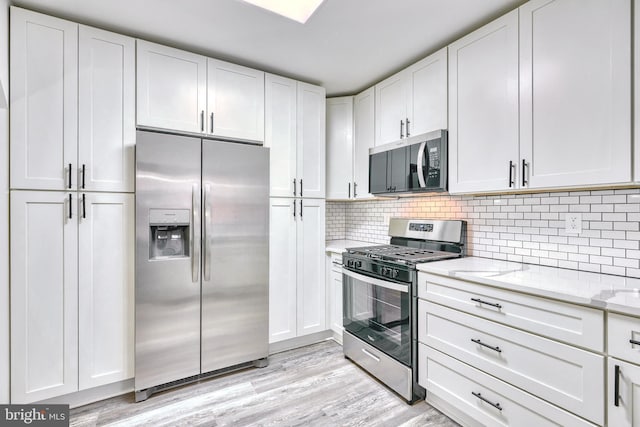 kitchen featuring white cabinetry, appliances with stainless steel finishes, light stone countertops, and light hardwood / wood-style floors