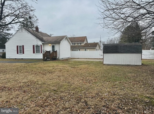 back of house featuring a shed and a yard