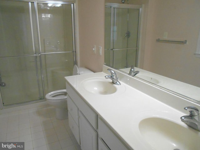 bathroom featuring a shower with door, vanity, tile patterned flooring, and toilet