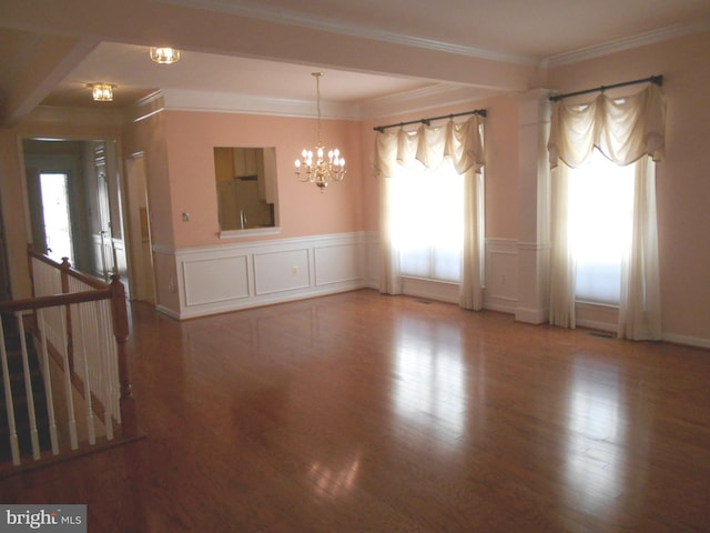 spare room featuring crown molding, plenty of natural light, hardwood / wood-style floors, and a notable chandelier