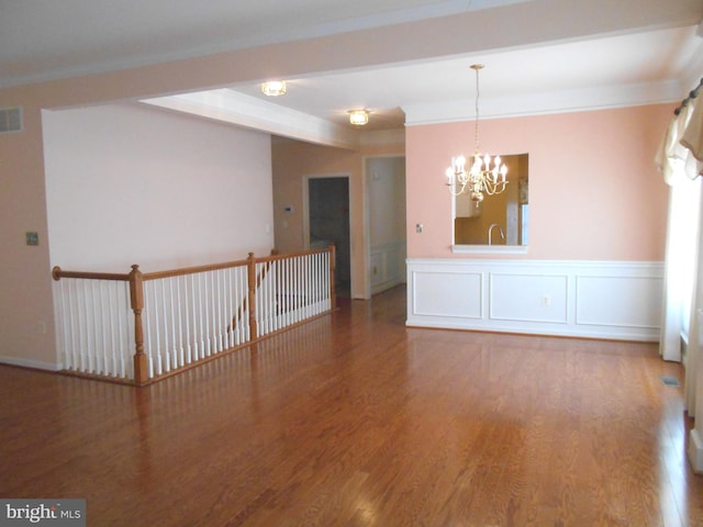 unfurnished room with crown molding, hardwood / wood-style floors, and a notable chandelier